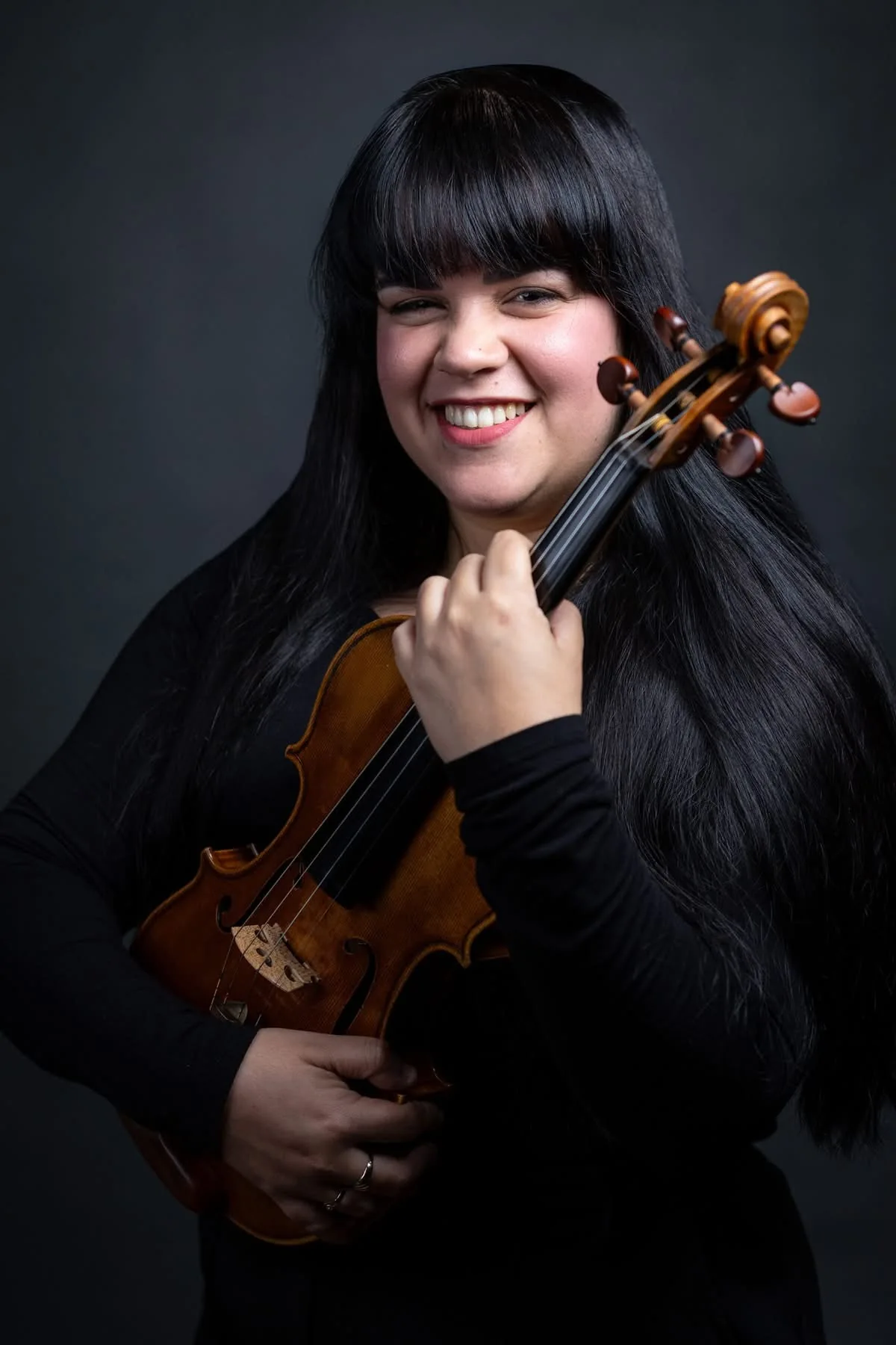 Yilian Concepción smiling with her violin in a professional portrait